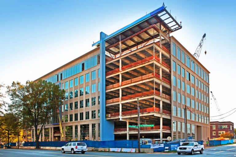 Partially constructed office building with cranes and street view.