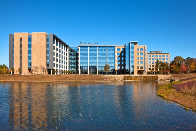 A large modern building with glass windows beside a calm body of water.