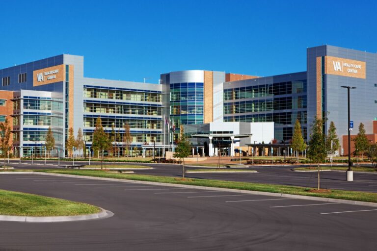 Modern healthcare center with a wide glass facade and surrounding parking lot.